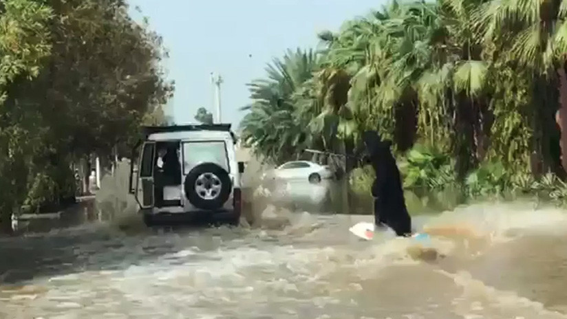 Mujer en burka surfea sobre calle inundada en Arabia Saudita